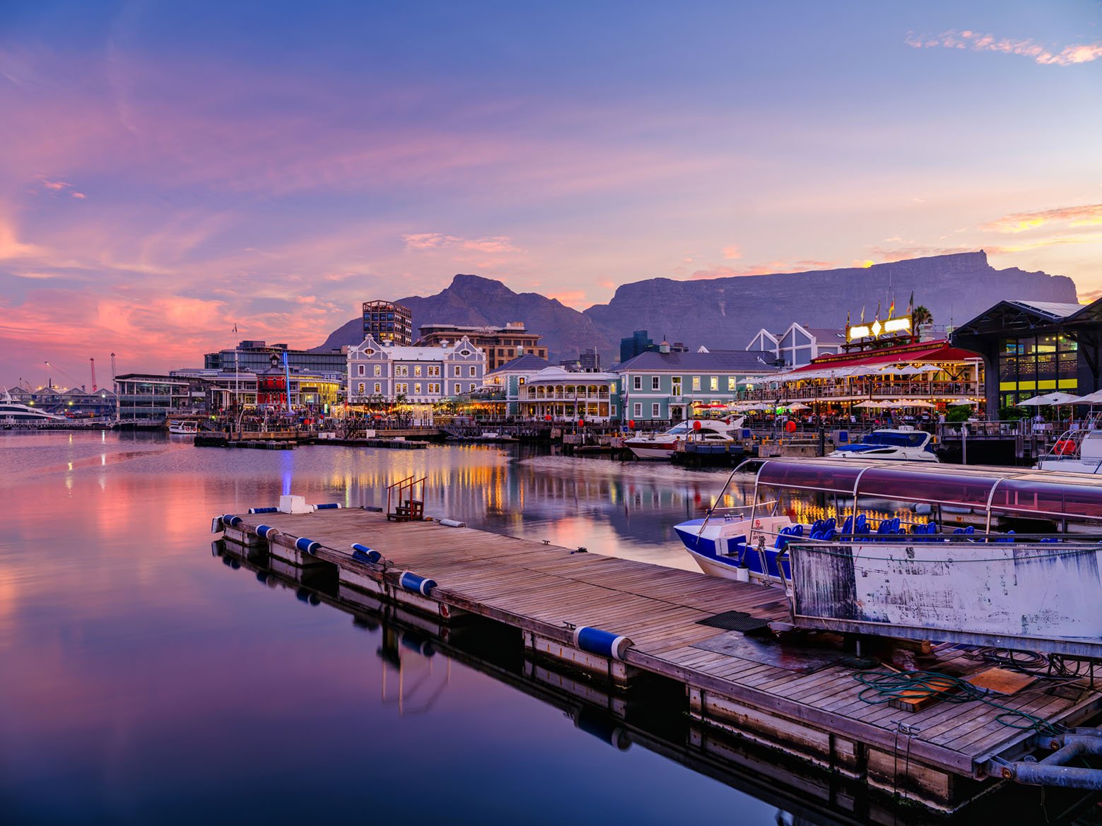 Victoria and Alfred, V and A waterfront lit up during a colorful sunset  with table mountain in the background, Cape Town, South Africa